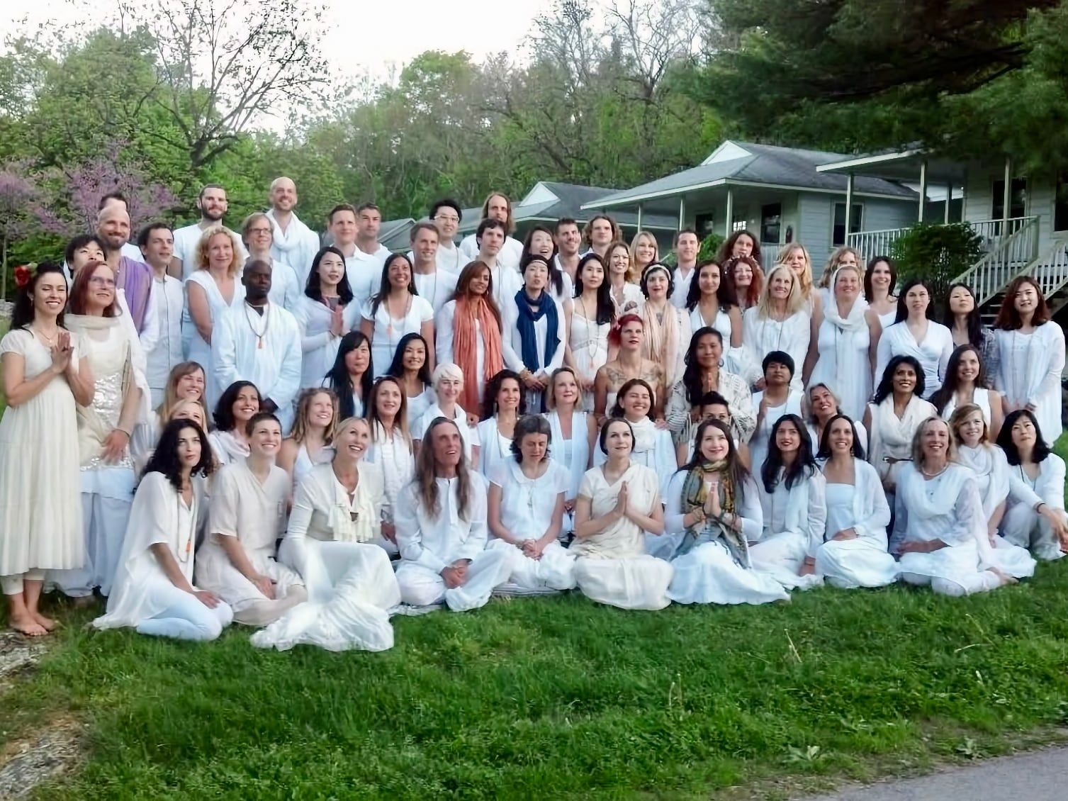 Abschlussfoto der Jivamukti-Ausbildung: Die Ausbildungsgruppe in festlichem Weiß, versammelt auf einer Wiese vor dem Retreat-Zentrum