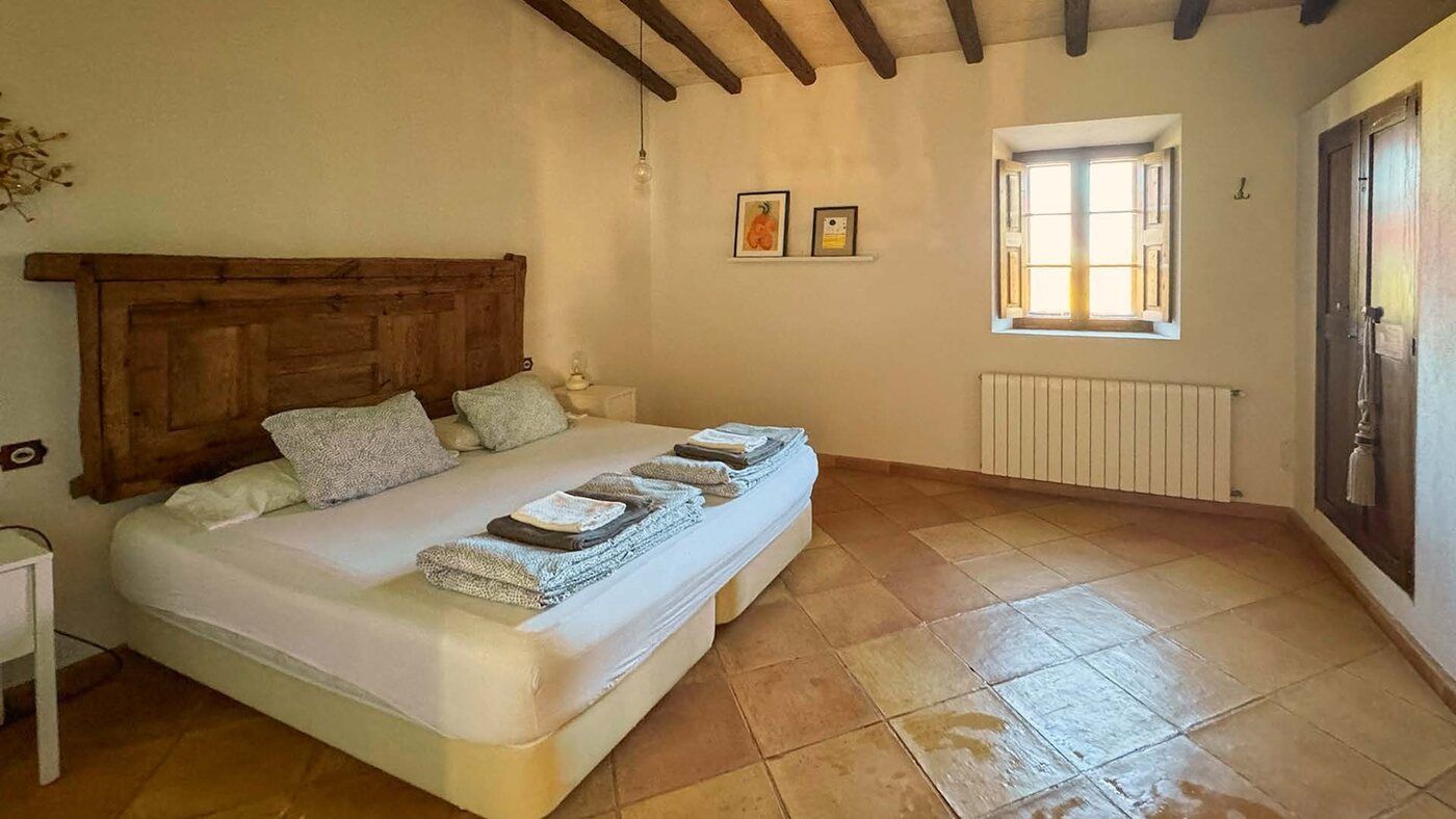 Schlafzimmer der Finca mit Holzbalkendecke und antikem Betthaupt