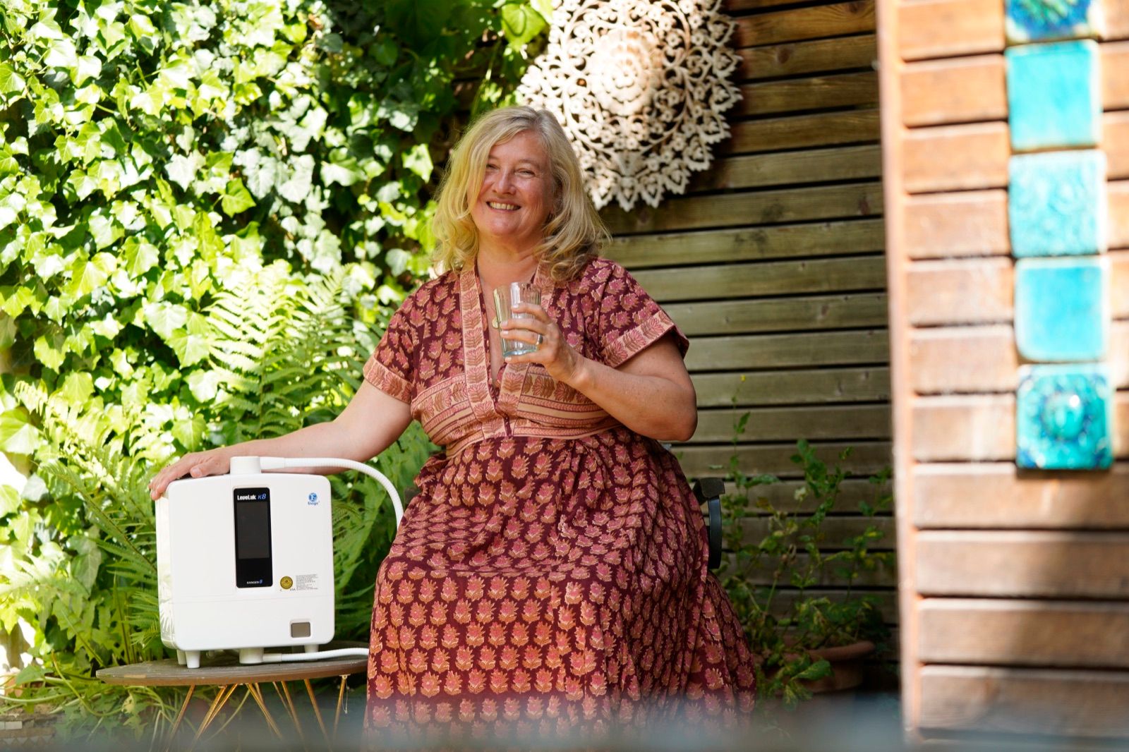 Jutta mit dem Kangenwassergerät und einem Glas Wasser