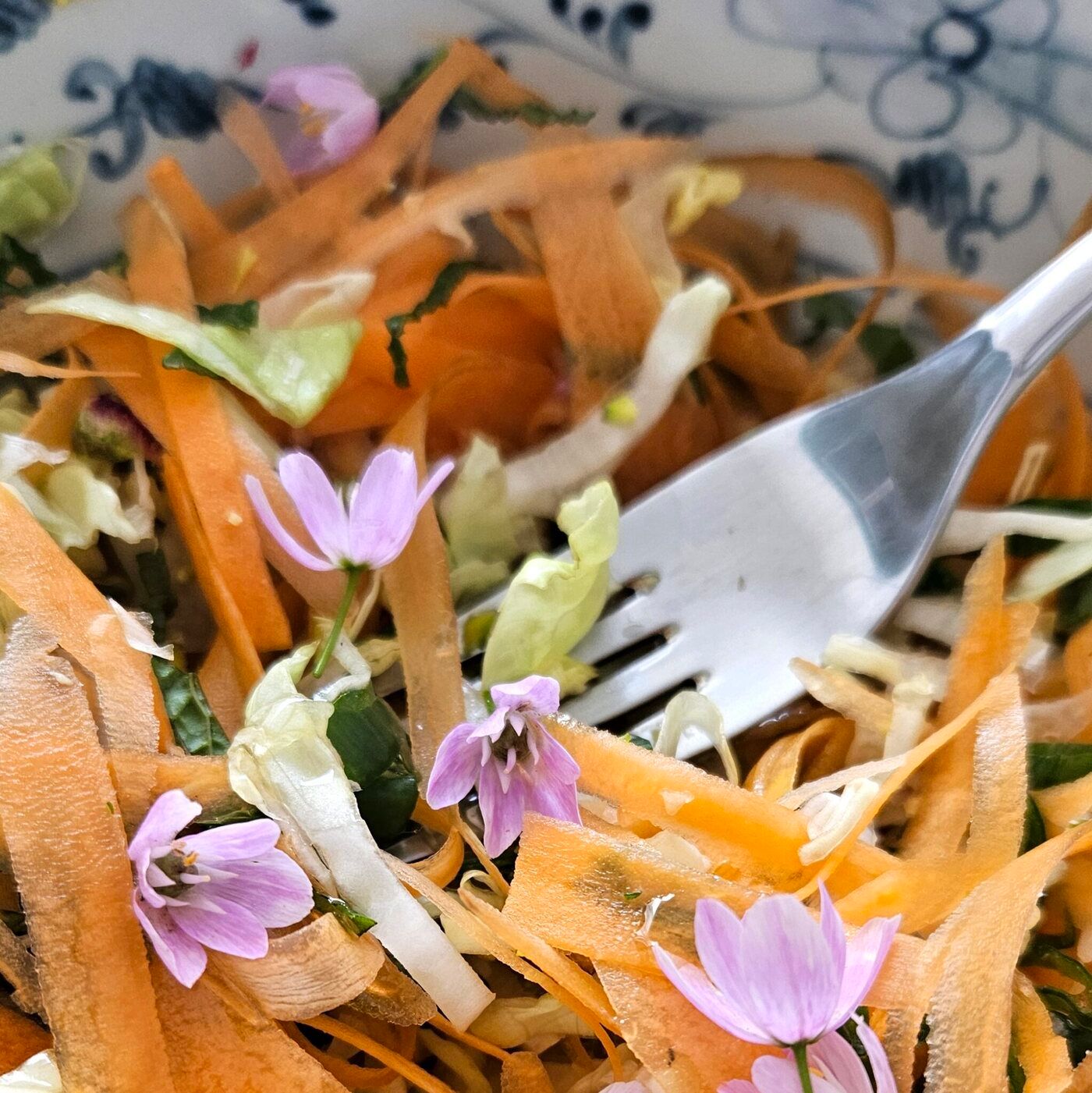 Wildkräuter-Salat mit Karottenstreifen und essbaren Blüten